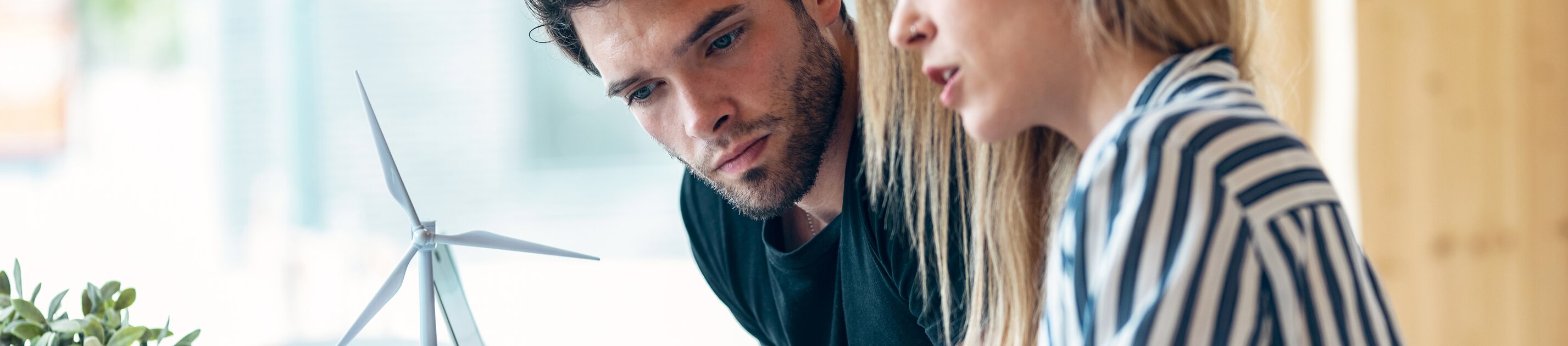 Zwei Personen besprechen nachhaltige Projekte und arbeiten gemeinsam an einem Tisch mit Windradmodell