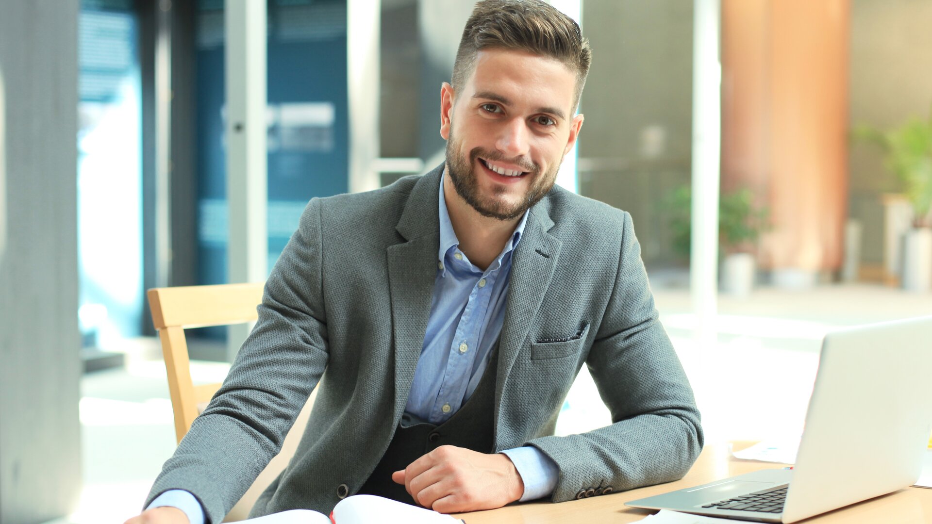 business mann am schreibtisch mit laptop und unterlagen