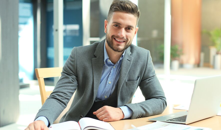 business mann am schreibtisch mit laptop und unterlagen