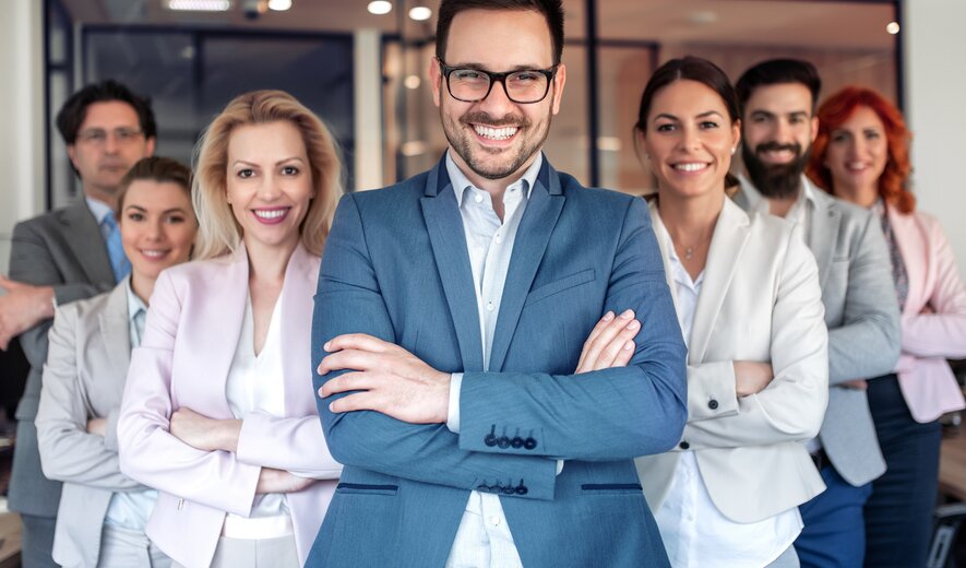 Team von Geschäftsleuten steht selbstbewusst lächelnd im modernen Büro.