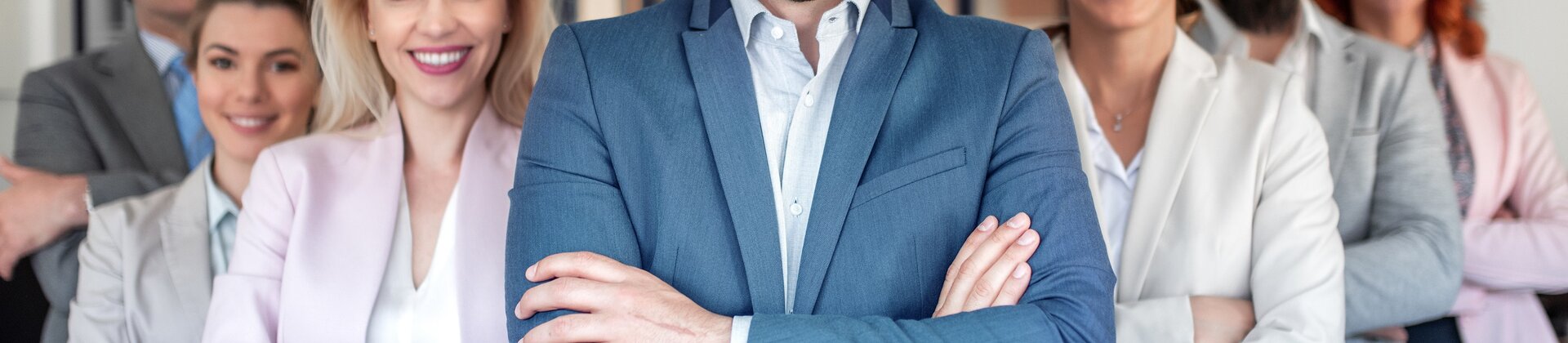 Team von Geschäftsleuten steht selbstbewusst lächelnd im modernen Büro.