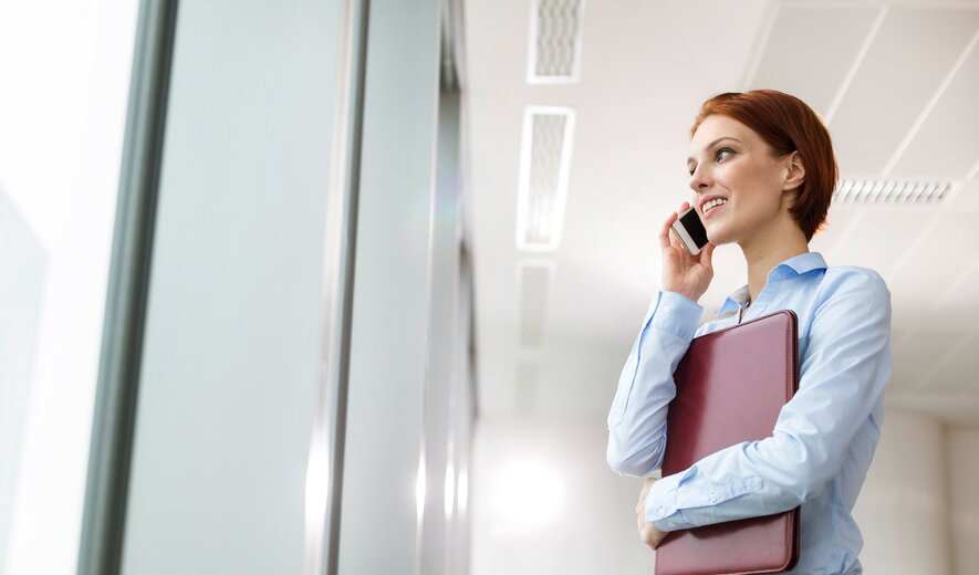 businessfrau telefoniert im büro und hält eine rote mappe