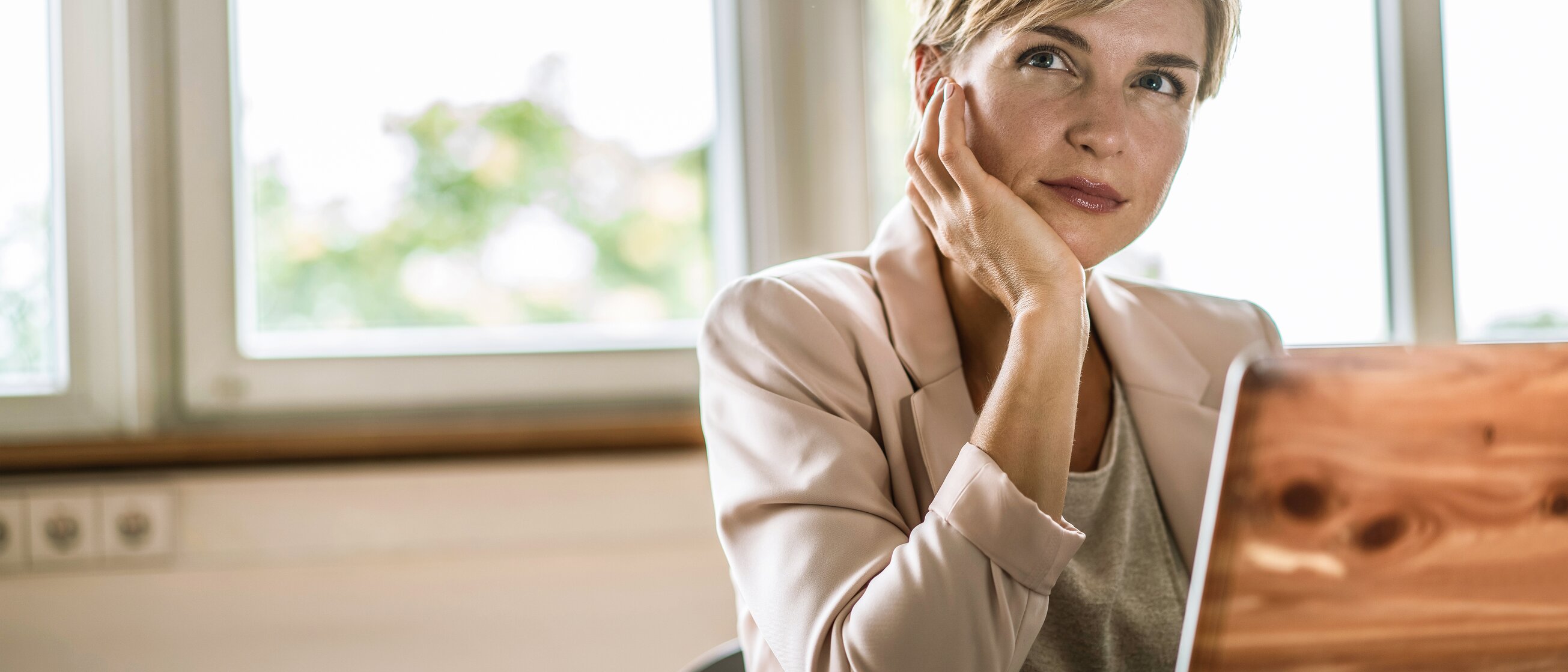 Frau sitzt nachdenklich am Schreibtisch mit Laptop – Weiterbildung zur IHK-Fachkraft Personalwesen für den erfolgreichen Einstieg ins Personalwesen