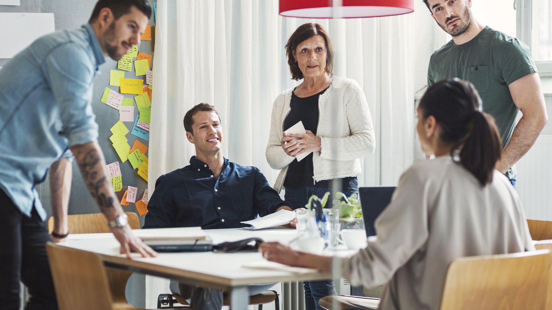 Teammeeting mit kreativer Diskussion und vielen Post-its an der Wand