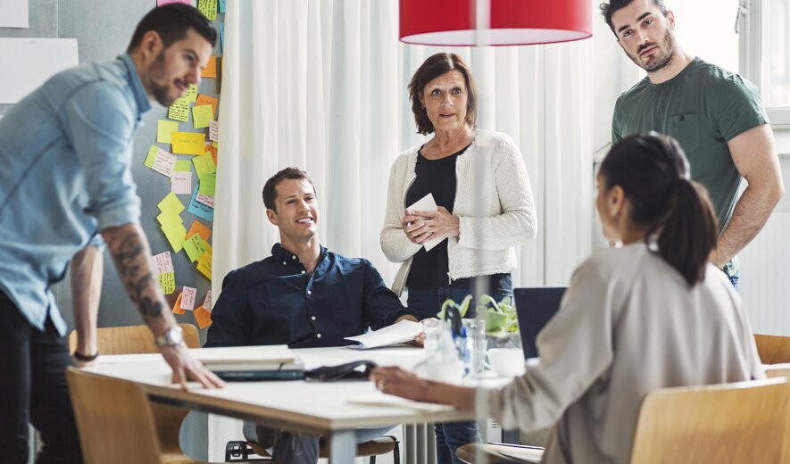 Teammeeting mit kreativer Diskussion und vielen Post-its an der Wand