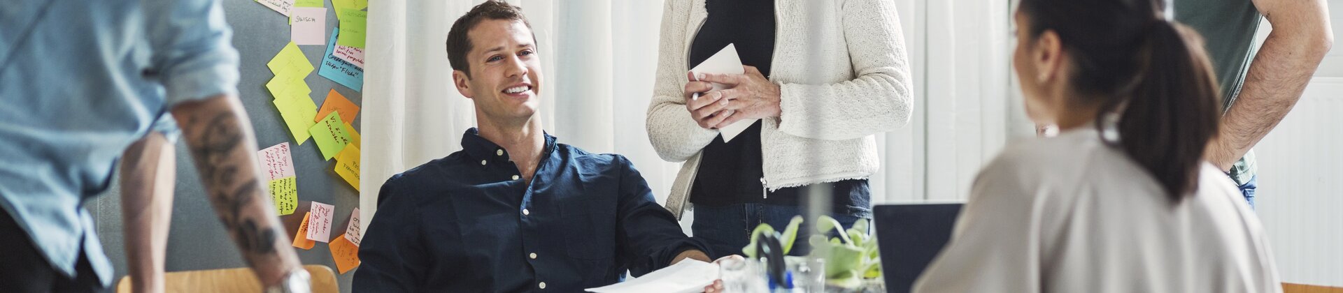 Teammeeting mit kreativer Diskussion und vielen Post-its an der Wand