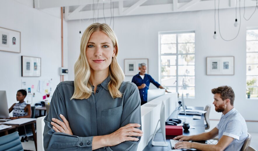 Führungskraft im modernen Büro steht selbstbewusst vor ihrem Team