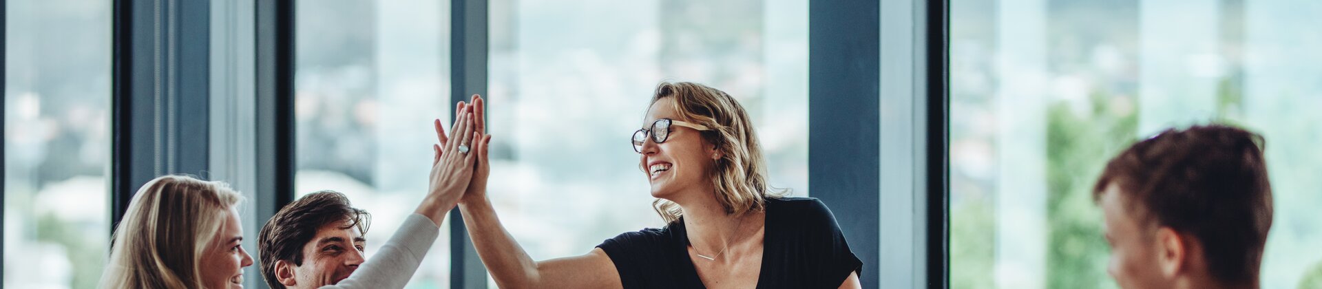 team jubelt beim erfolgreichen projektmeeting und gibt sich ein high five im modernen büro