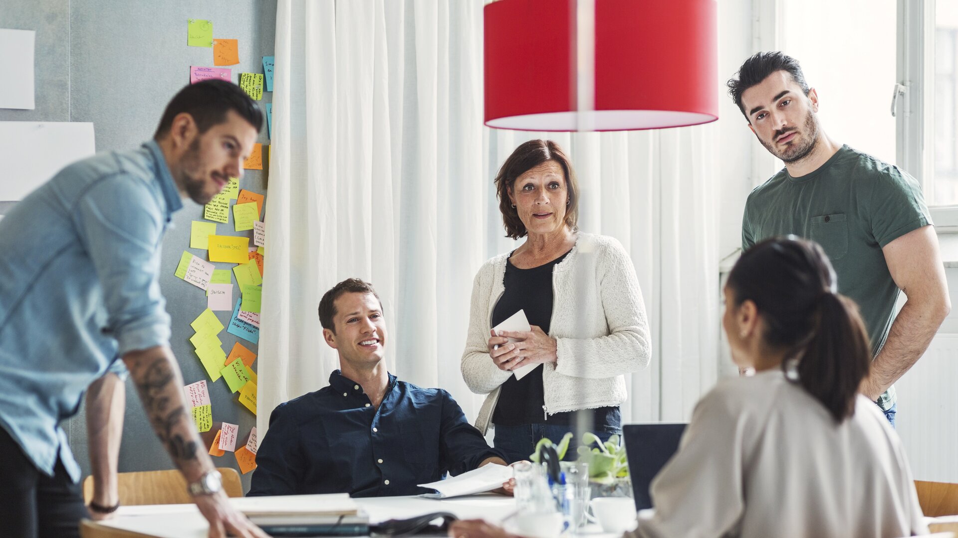 Teammeeting mit kreativer Diskussion und vielen Post-its an der Wand