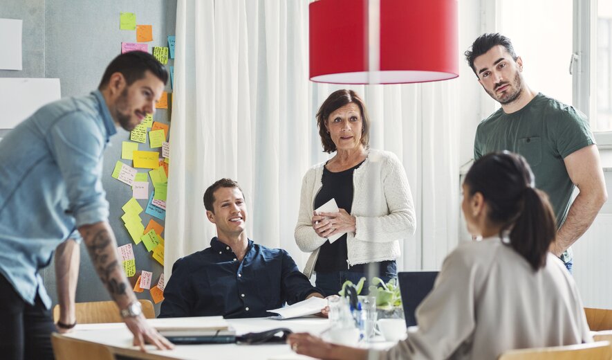 Teammeeting mit kreativer Diskussion und vielen Post-its an der Wand
