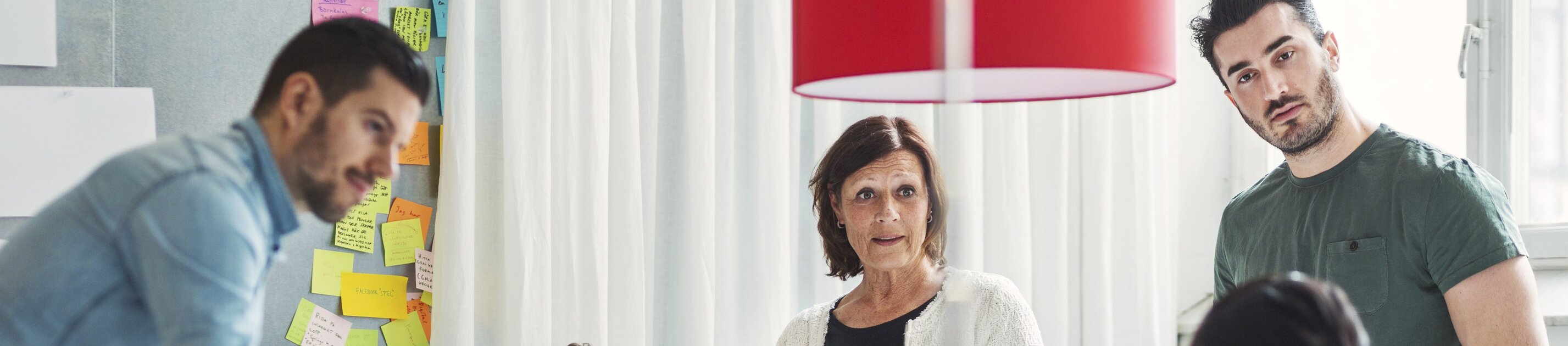 Teammeeting mit kreativer Diskussion und vielen Post-its an der Wand