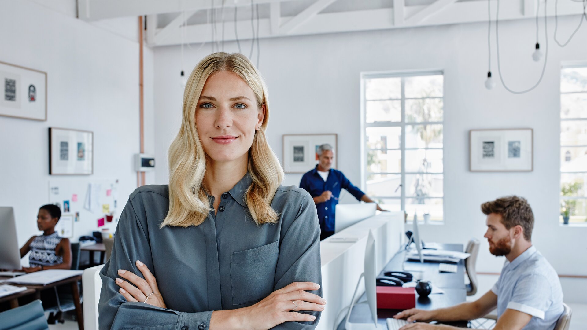 Führungskraft im modernen Büro steht selbstbewusst vor ihrem Team