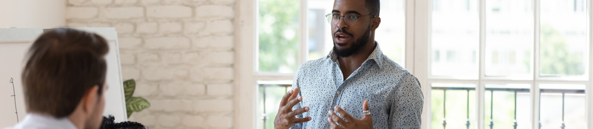 Teammeeting in modernem Büro, Mitarbeiter präsentiert Ideen vor Kolleginnen und Kollegen