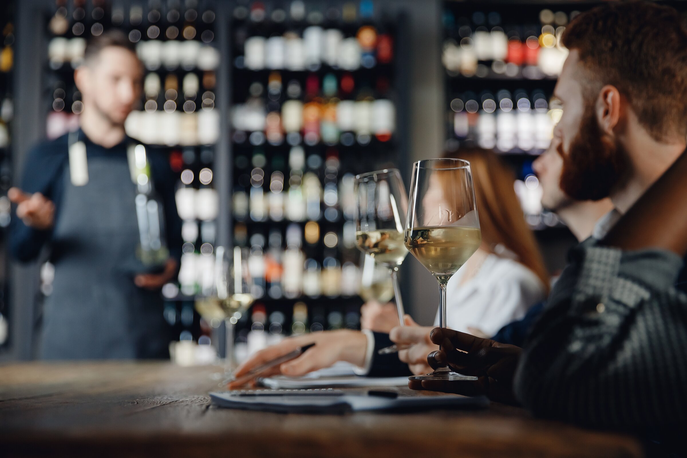 Weiterbildung in der Sommellerie: Ein Trainer steht vor Teilnehmer/-innen und erklärt etwas über einen Wein. 