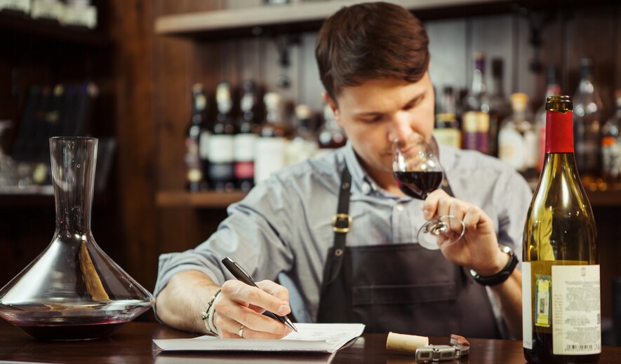 Sommelier degustiert Rotwein und macht professionelle Verkostungsnotizen an der Bar