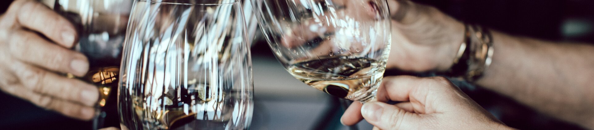 Personen stoßen mit Weißwein in elegantem Ambiente an.