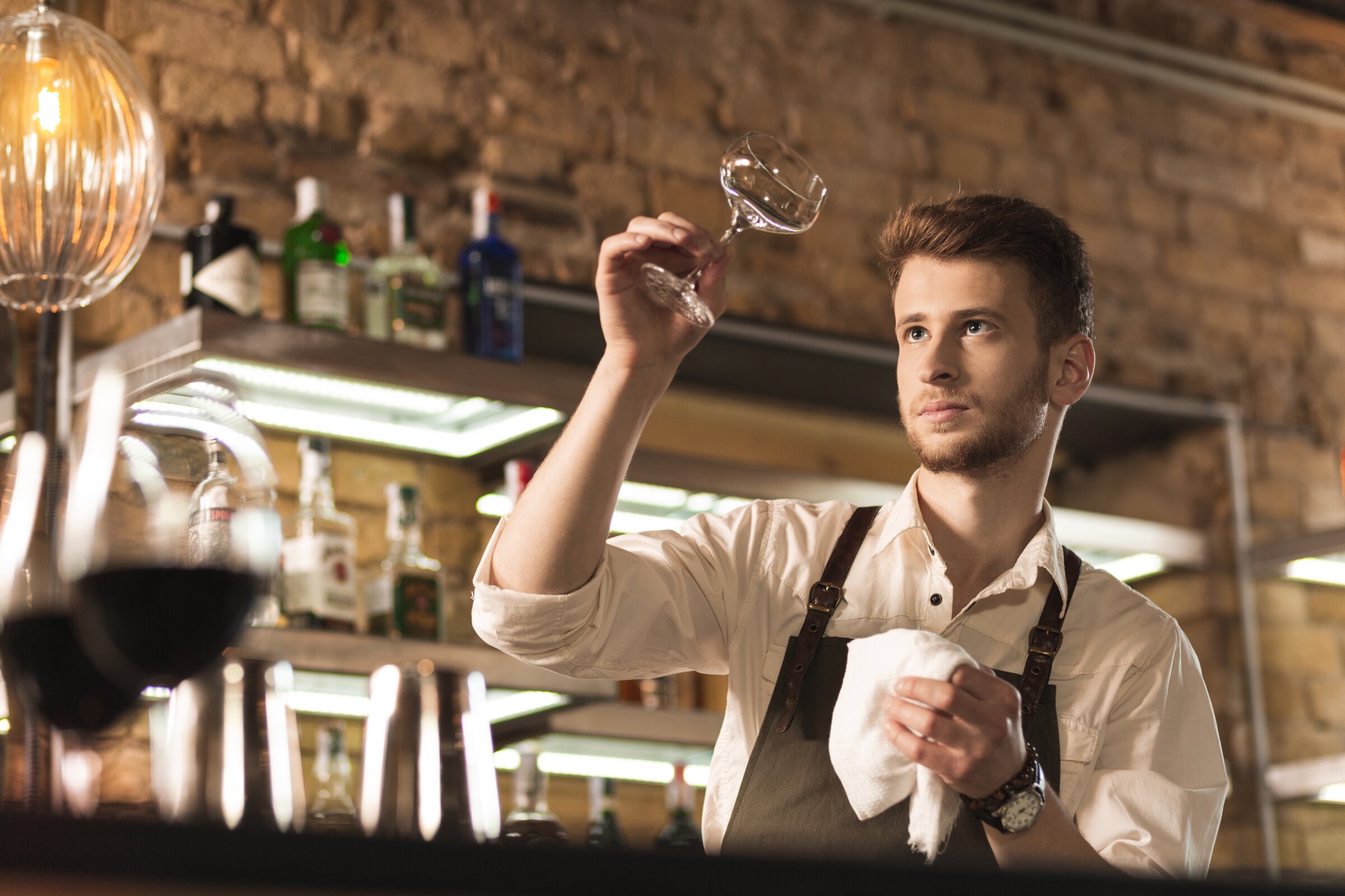 Weiterbildung in der Sommellerie: Ein Sommelier poliert ein Weinglas. 