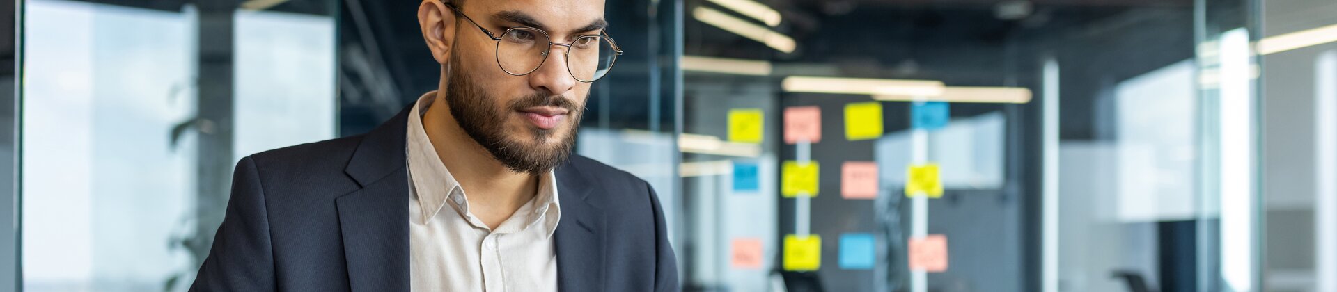 Businessman working on laptop in modern office, analysing documents and data