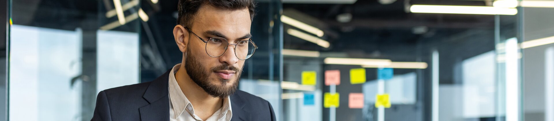 Businessman working on laptop in modern office, analysing documents and data
