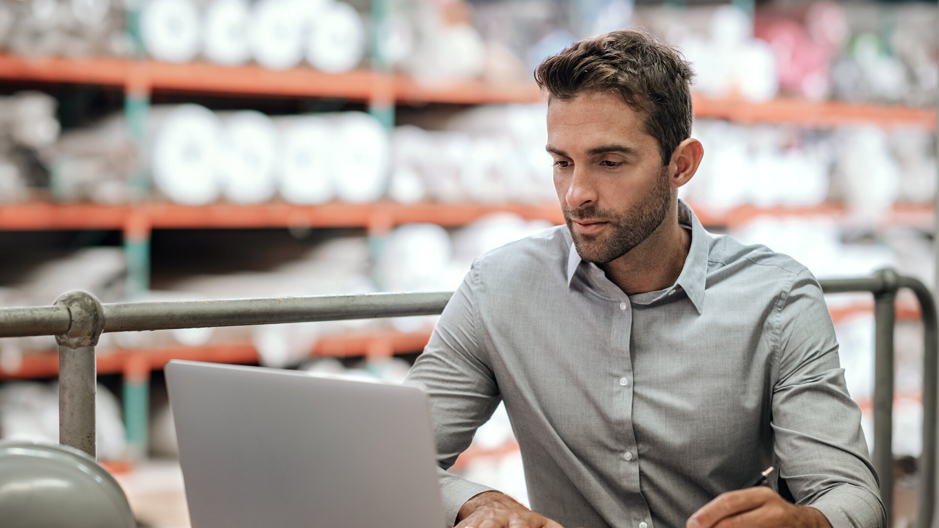 Mitarbeiter arbeitet im Lager an einem Laptop und erstellt Notizen