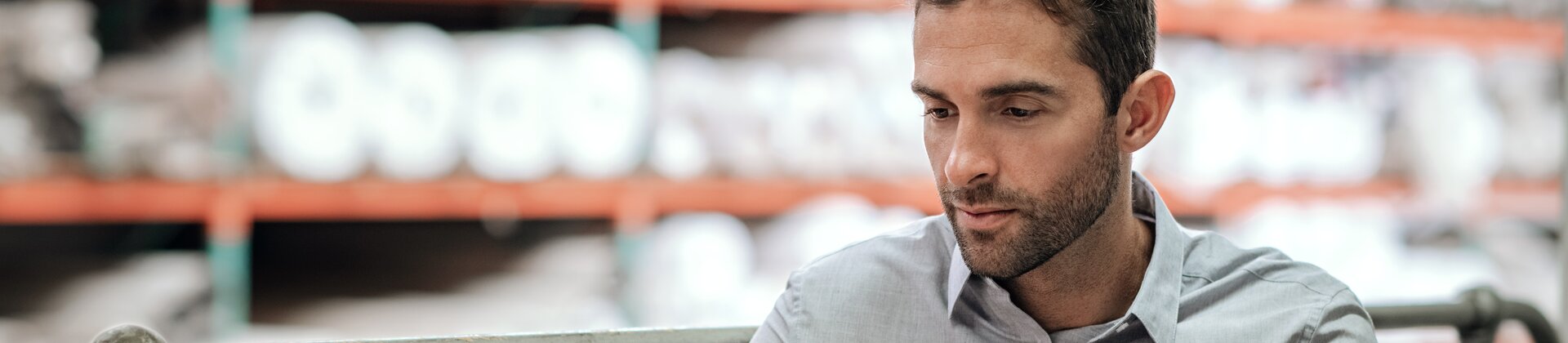 Mitarbeiter arbeitet im Lager an einem Laptop und erstellt Notizen