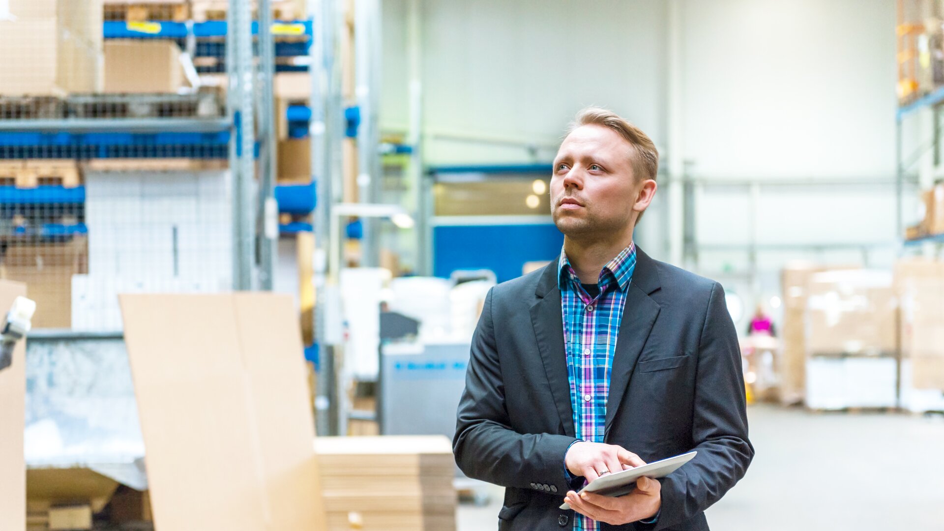 Lagerleiter mit Tablet inspiziert Waren im modernen Logistiklager