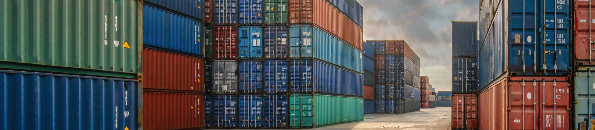 Gestapelte bunte Frachtcontainer im Hafen unter wolkigem Himmel