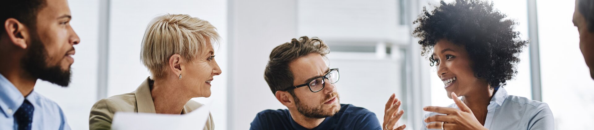 Weiterbildung Feedback- und Mitarbeitergespräche: Mitarbeitende führen ein Gespräch in einer Besprechungsrunde.