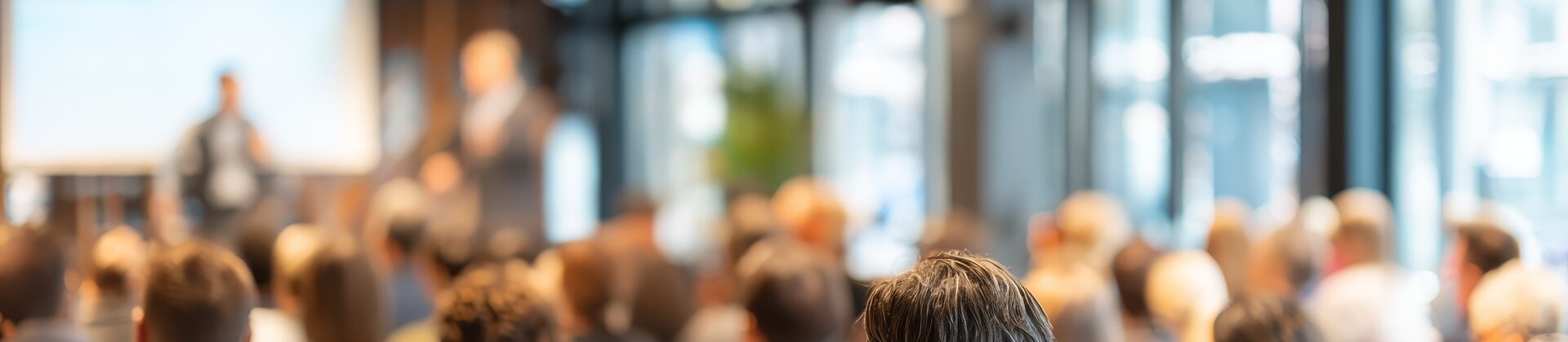 Teilnehmer/-innen einer Infoveranstaltung zu Weiterbildungen in Ingolstadt hören einem Vortrag im modernen Konferenzraum zu.