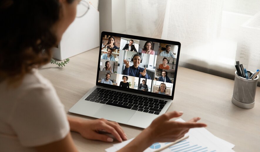 Teilnehmerin schaut auf ihren Laptop, auf dem man weitere Teilnehmer/-innen sieht, während einer Online-Weiterbildung.