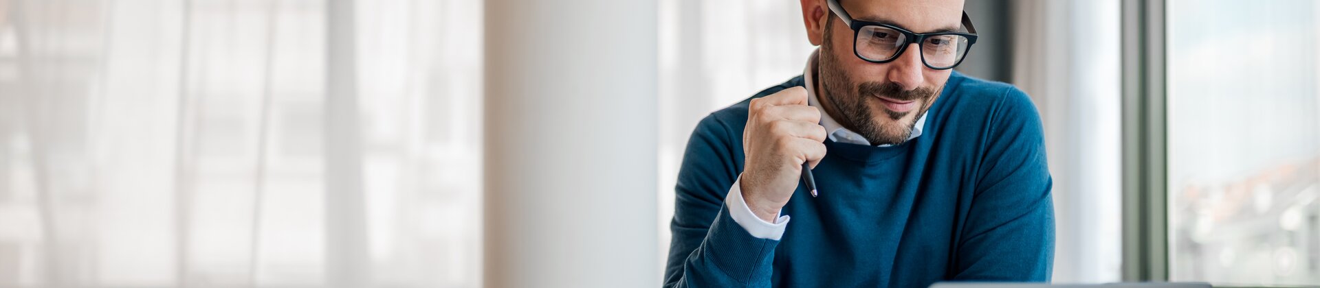 Ein Mann sitzt vor seinem Laptop und arbeitet an seiner LinkedIn-Strategie. 