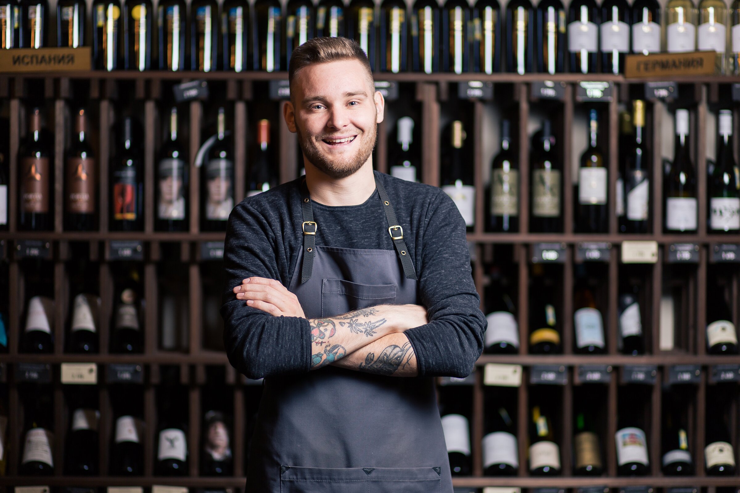 Weiterbildung Junior Sommelier/-ière IHK: Sommelier steht vor Weinregalen und präsentiert seine Fachkompetenz.