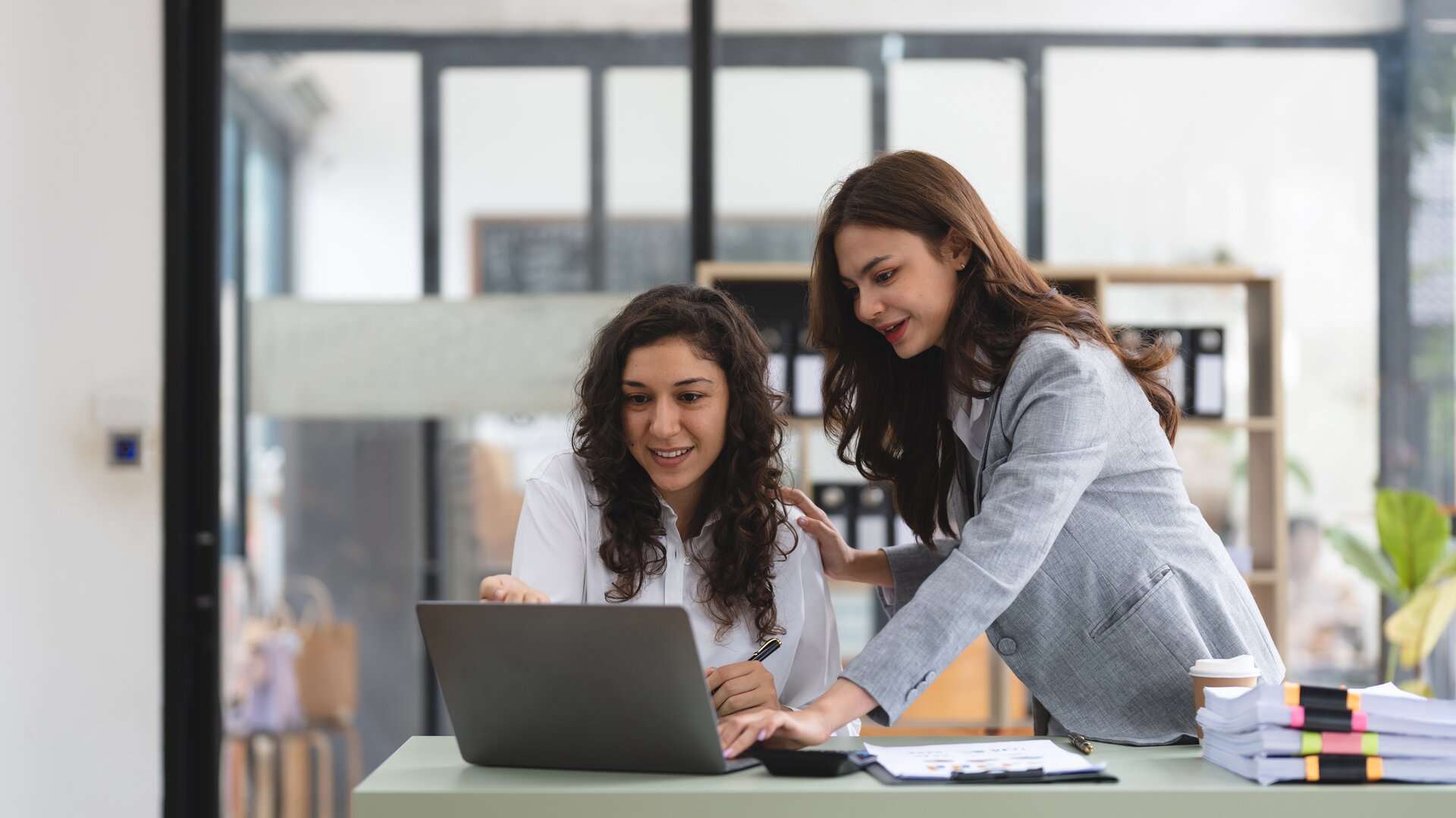 Weiterbildung New Work Assistenz IHK: Zwei Kolleginnen arbeiten gemeinsam am Laptop an modernen Assistenzaufgaben.