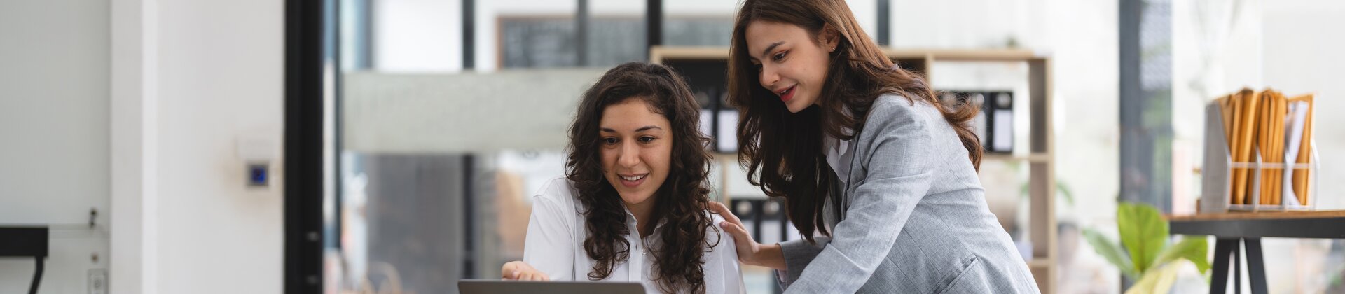 Weiterbildung New Work Assistenz IHK: Zwei Kolleginnen arbeiten gemeinsam am Laptop an modernen Assistenzaufgaben.