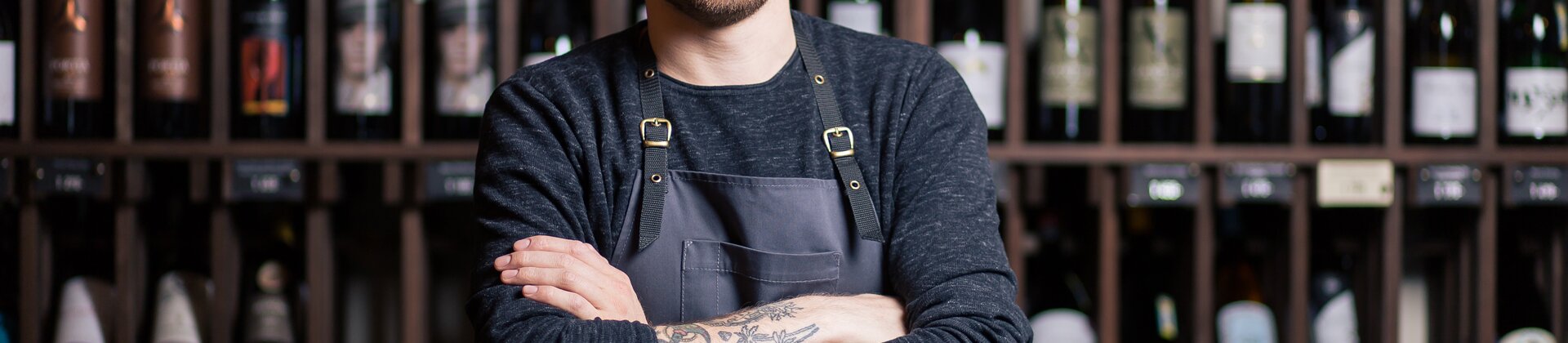 Weiterbildung Junior Sommelier/-ière IHK: Sommelier steht vor Weinregalen und präsentiert seine Fachkompetenz.