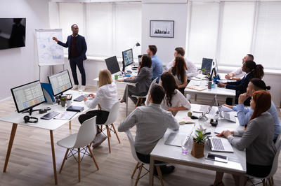 Trainer moderiert Workshop mit Team im modernen Seminarraum – Moderationstraining für strukturierte Meetings und erfolgreiche Teamkommunikation.