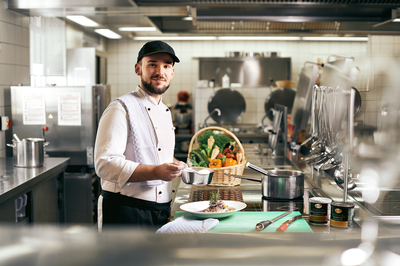 Koch bereitet frische Gerichte in der Küche der Akademie Westerham zu – regionale Kulinarik und Genussmomente für Tagungsgäste