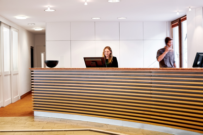 Rezeption der Akademie Westerham mit Mitarbeitenden beim Gästeempfang als Anlaufstelle für Raum- und Zimmeranfragen