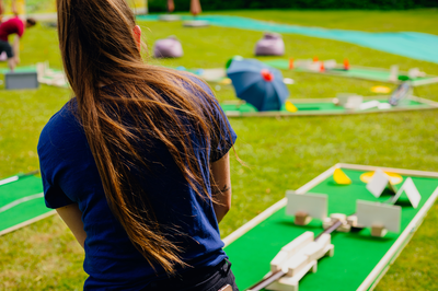 Person auf einer Wiese baut eine bunte Minigolfbahn beim Selfmade-Minigolf-Teamturnier