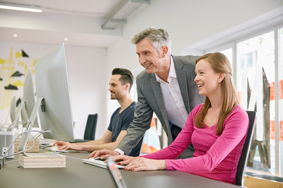 Führungskraft unterstützt motiviertes Team im Büro, um Arbeitgeberattraktivität trotz Fachkräftemangel zu stärken.