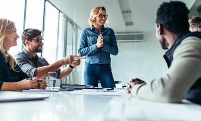 Team lacht während eines Meetings, in dem Maßnahmen für mentale Gesundheit und Achtsamkeit besprochen werden.