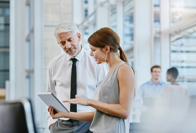 Mann und Frau besprechen Unterlagen in modernem Büro – Symbolbild für die Weiterbildung zum Geprüften Industriefachwirt an der IHK Akademie Mühldorf.