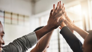 Shot of a group of young people giving each other a high five during their workout in a gym.