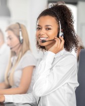 Call center worker accompanied by her team. Smiling customer support operator at work. Young employee working with a headset.