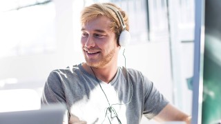 Creative office man working on his computer and wearing a headset