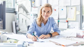 Portrait of smiling woman doing paperwork at desk in office