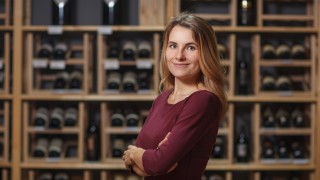 Attractive woman sommelier in wine cellar background.