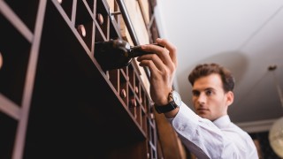 Selective focus of sommelier taking wine bottle from rack in restaurant