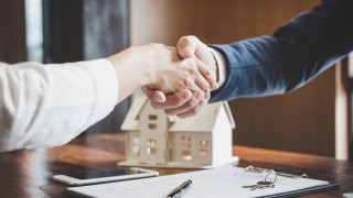 Real estate agent and customers shaking hands together celebrating finished contract after about home insurance and investment loan, handshake and successful deal.