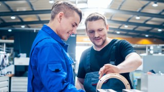 Skillful master discussing a workpiece with his apprentice or trainee